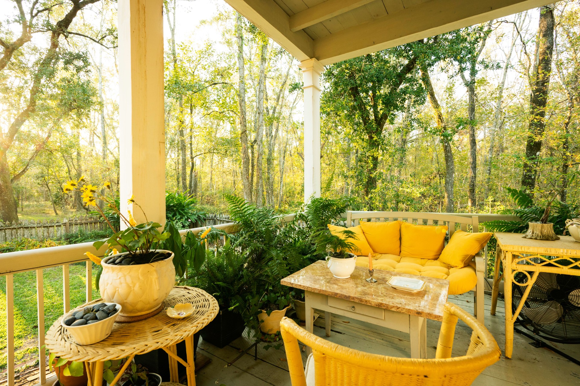 Enticing porch with yellow cushions and plants at Maison Madeleine, an authentic 1840 French Creole cottage, Lake Martin, Breaux Bridge, Louisiana, USA